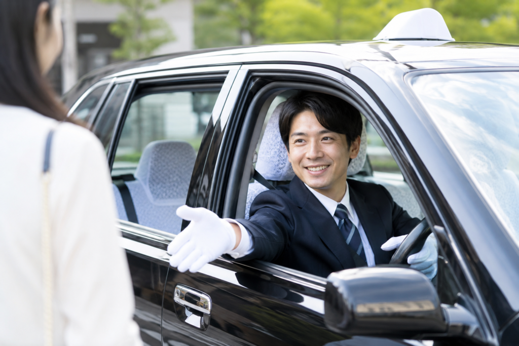 タクシードライバーがお客様を笑顔で迎え、安心・安全な送迎サービスを提供している様子。地域密着型のタクシー会社で働くイメージ画像